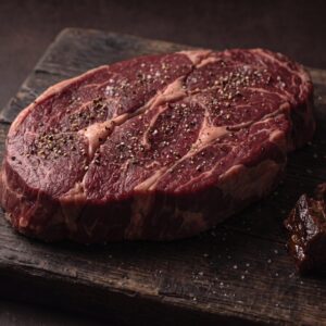 Rå bison tykkam med salt og peber på et mørkt træbræt, med mørt braiseret kød ved siden af.