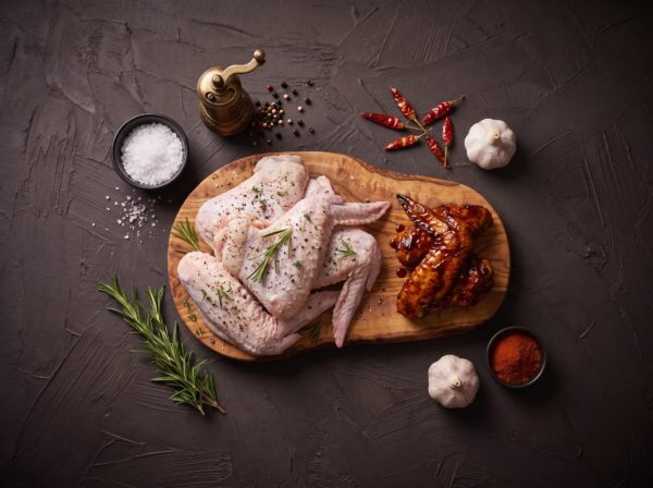 Rå økologiske kalkunvinger med chili og paprika på træbræt