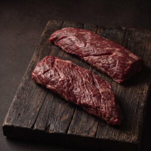 To rå nyretapper (onglet) af græsfodret dansk kødkvæg på et mørkt træbræt.