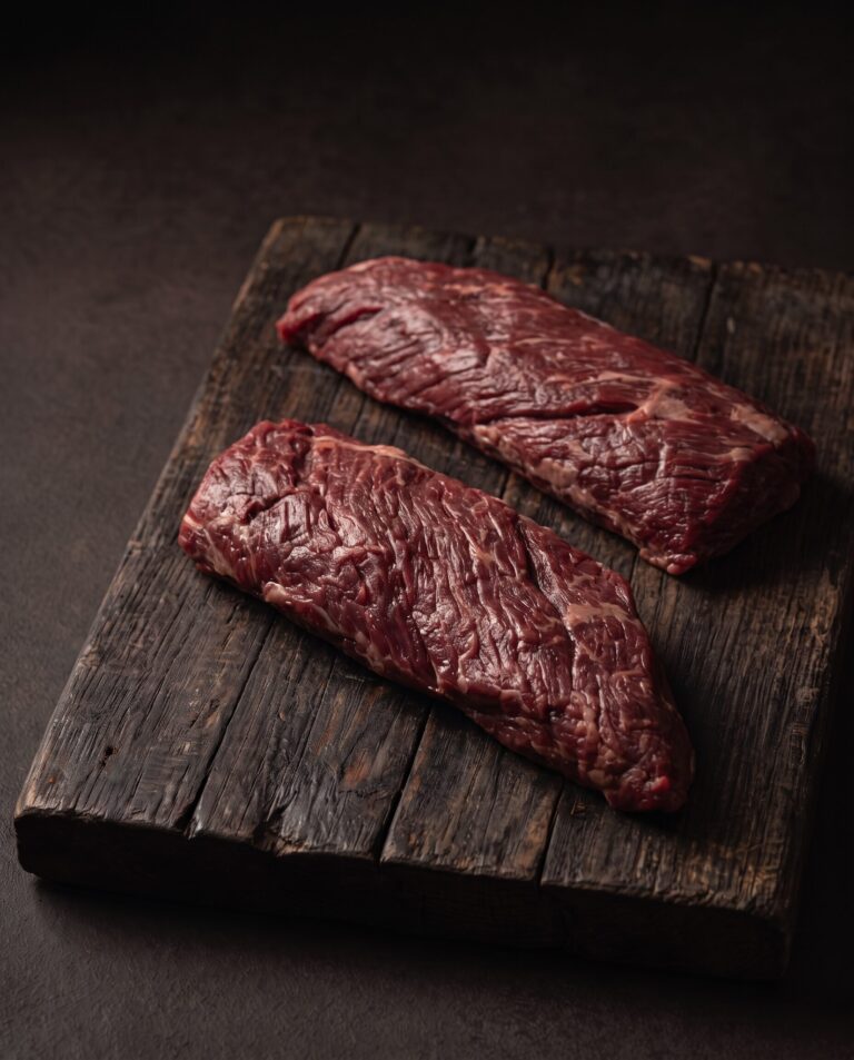To rå nyretapper (onglet) af græsfodret dansk kødkvæg på et mørkt træbræt.
