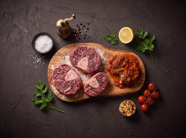 Rå osso buco skiver på træbræt med krydderier og tomat