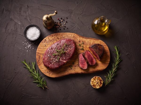Rump heart filet med salt, peber og timian på et oliventræsbræt, med stegte skiver.